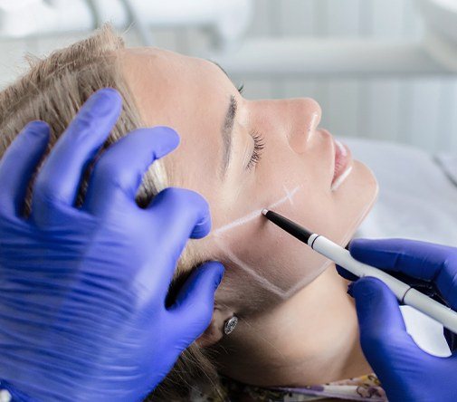 dentist using white marker on woman's face