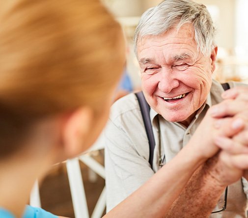 Senior patient in Marysville smiling thankfully with dentist after getting dentures
