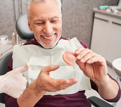 A man looking at his new dentures