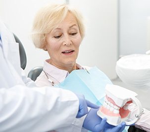 Dentist showing patient how dentures preserve surrounding teeth on a model
