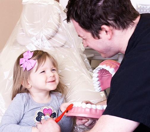 Marysville dentist with young girl smiling