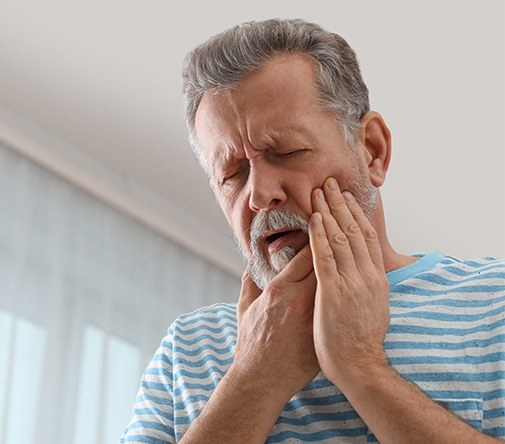 man holding cheek and jaw in severe pain