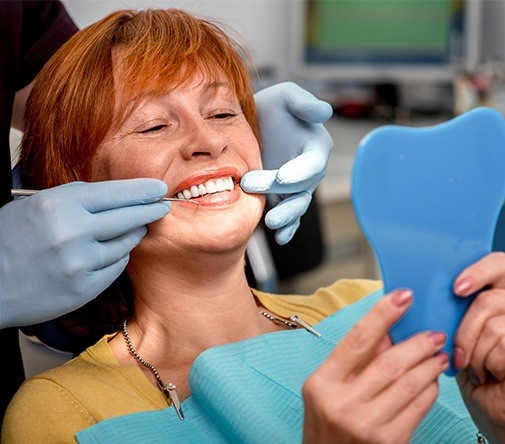 woman checking smile in light blue mirror