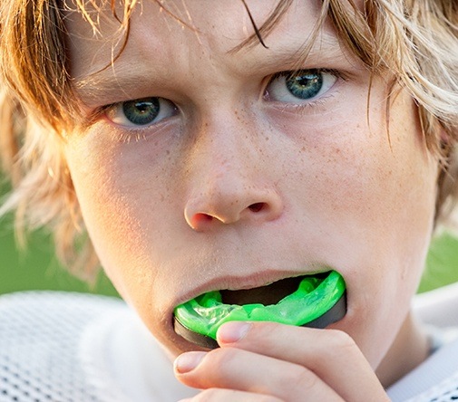 boy putting in green mouthguard