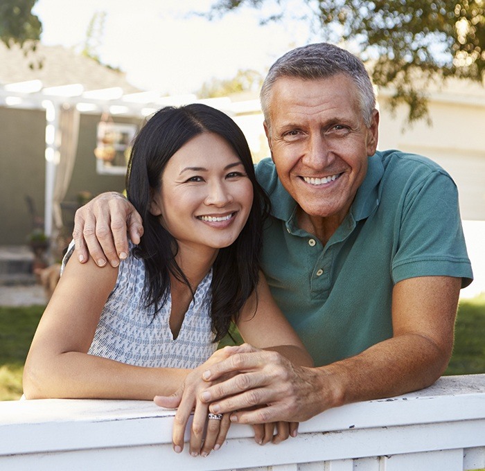 man with arm around woman smiling