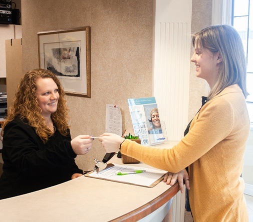 patient in yellow handing over dental card