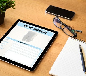 Dental insurance form on tablet on desk with notepad.