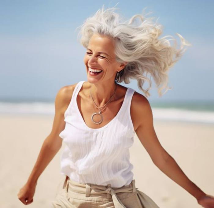 Happy senior woman playing on the beach