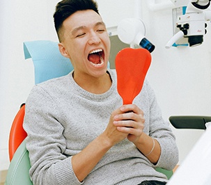 Male dental patient looking in a handheld mirror