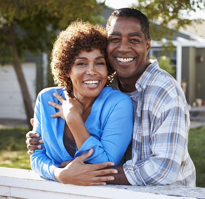 husband and wife hugging and smiling outside