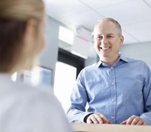 man at front desk smiling at worker