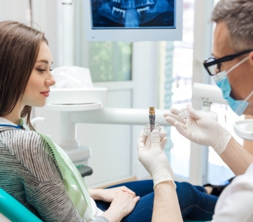 dentist showing woman how implant works