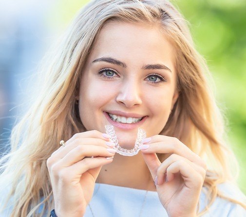 blonde woman holding invisalign