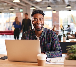 Man smiling while working on laptop in office