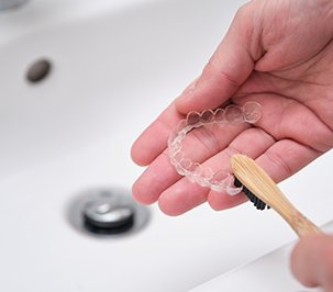 Patient using toothbrush to clean clear aligner