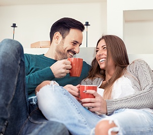 Couple smiling while drinking coffee together at home