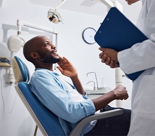 Smiling patient talking to dentist with clipboard.