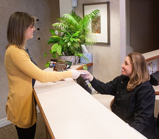 patient in yellow at front desk smiling at worker