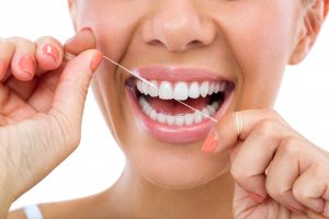 woman smiling while flossing his teeth