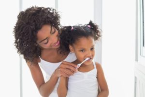 parent teaching their child how to brush their teeth