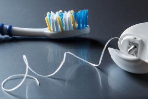 Toothbrush and dental floss sitting on a gray surface