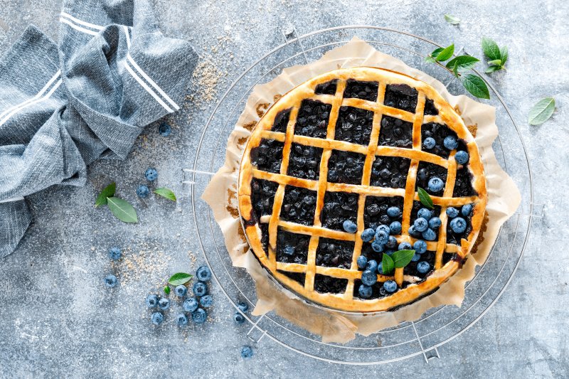 a beautiful blueberry pie inside a pie plate and sitting on a table 