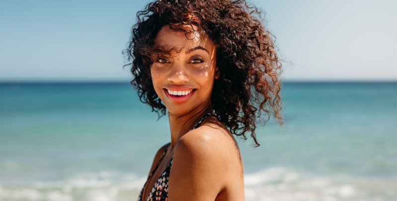 a young female smiling while on the beach during vacation