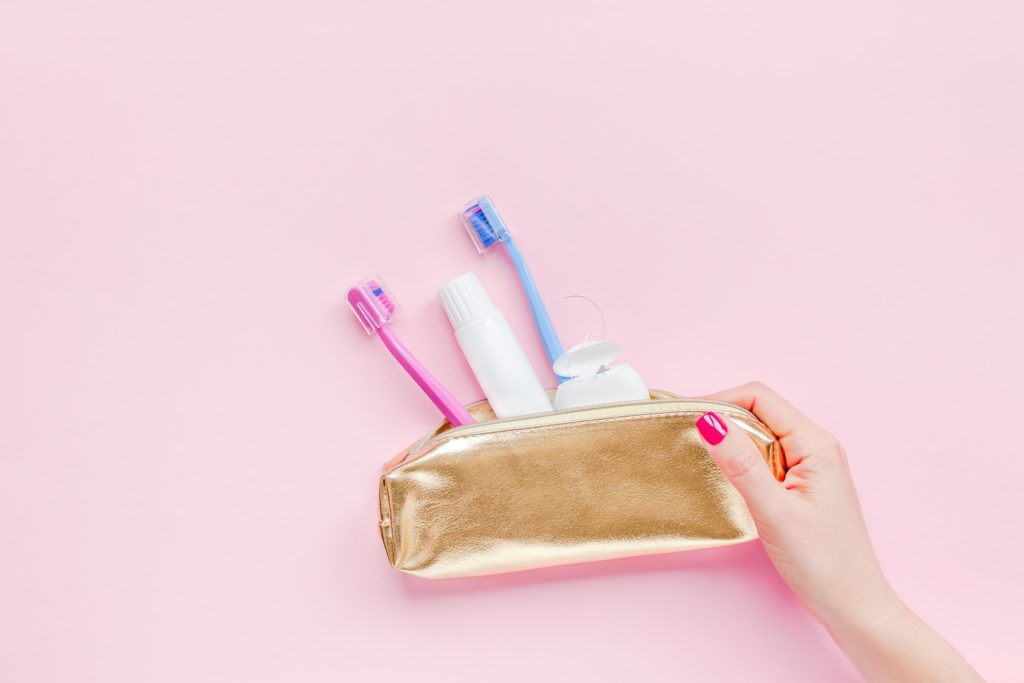 Woman holding gold dental travel kit