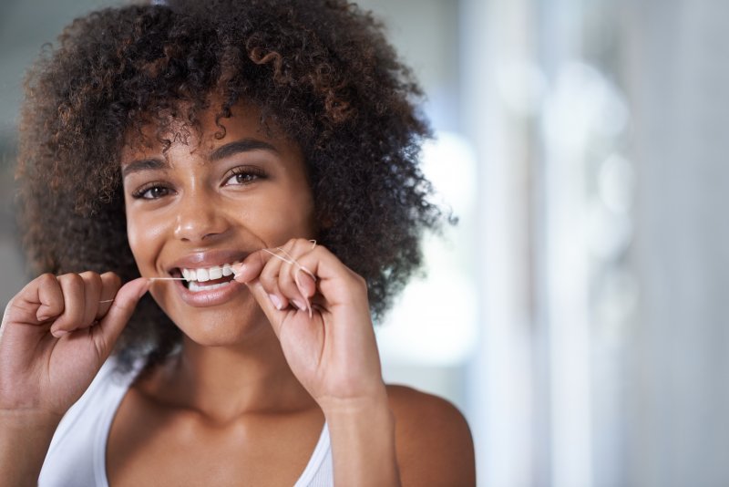 young woman flossing her teeth