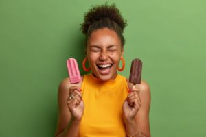 a woman holding two icy treats in her hands during the summer