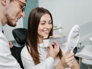 Woman looking at veneers in dentist's chair. 
