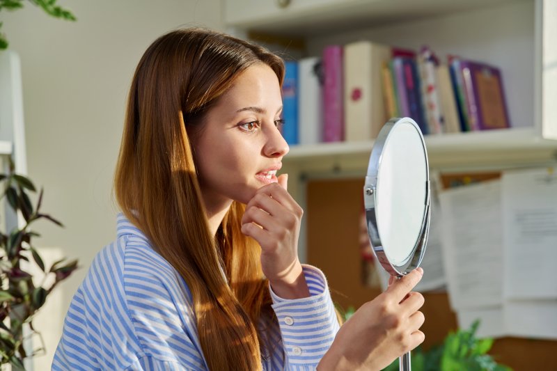 Patient checking smile in mirror after cosmetic dentistry